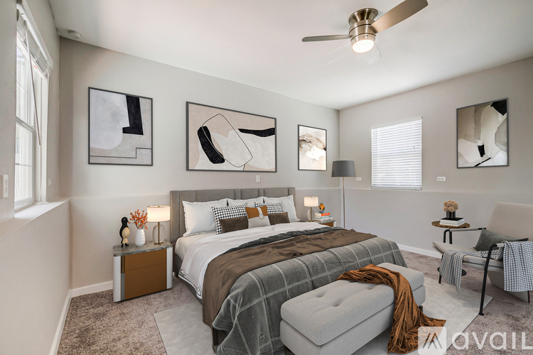 A bedroom with a large bed, a ceiling fan, and artwork on the wall.