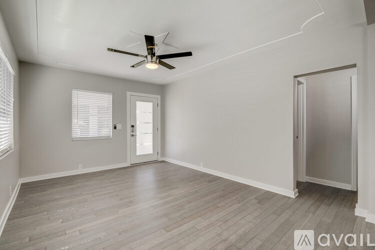 A spacious room with a ceiling fan and wooden flooring.
