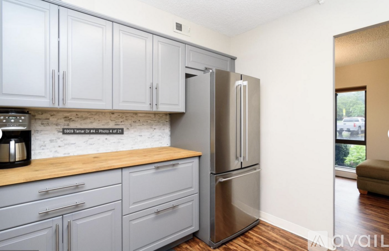 A kitchen with grey cabinets and a stainless steel refrigerator.