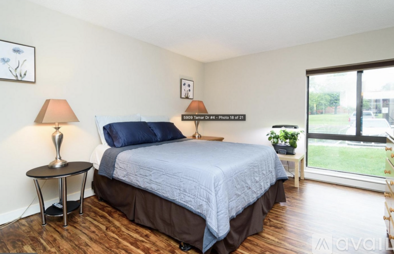 A bedroom with a bed, a side table, and a window.
