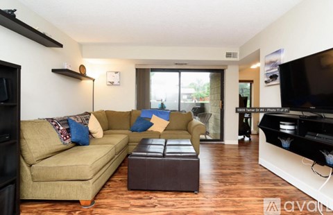 A living room with a beige couch and a brown ottoman.