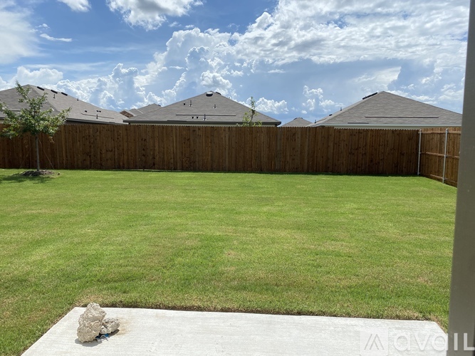 A backyard with a wooden fence and a large grassy area.