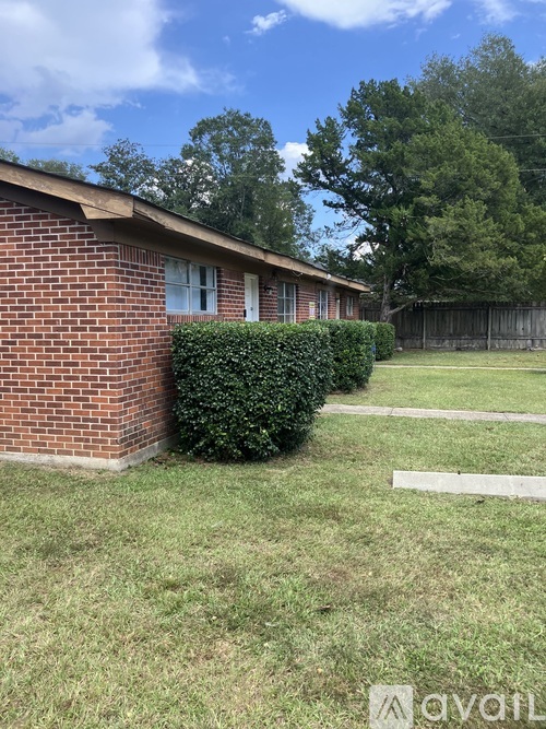 A small red brick house with a white fence in front.