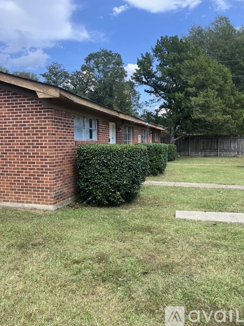 A small red brick house with a white fence in front.