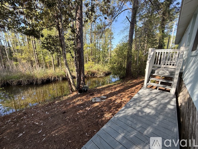 A wooden deck overlooks a body of water with trees in the background.