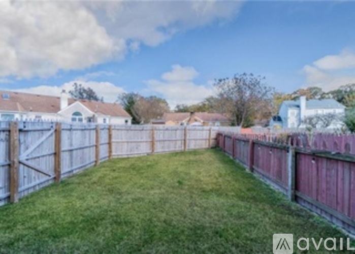 A backyard with a wooden fence and a grassy area.