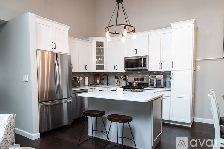A kitchen with white cabinets and a stainless steel refrigerator.