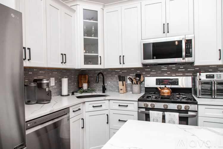 A modern kitchen with white cabinets and stainless steel appliances.