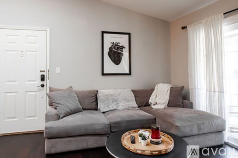 A living room with a grey couch and a framed picture on the wall.