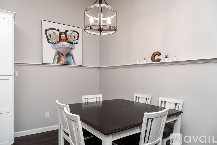 A dining room with a brown table and white chairs.