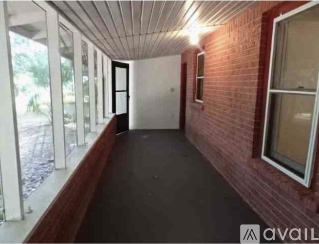 A long hallway with a brick wall and a white door.