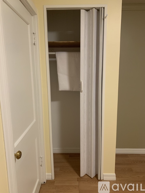 A white door with a gold handle is open to a room with a white curtain.