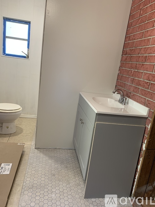 A bathroom with a toilet, sink, and a window.