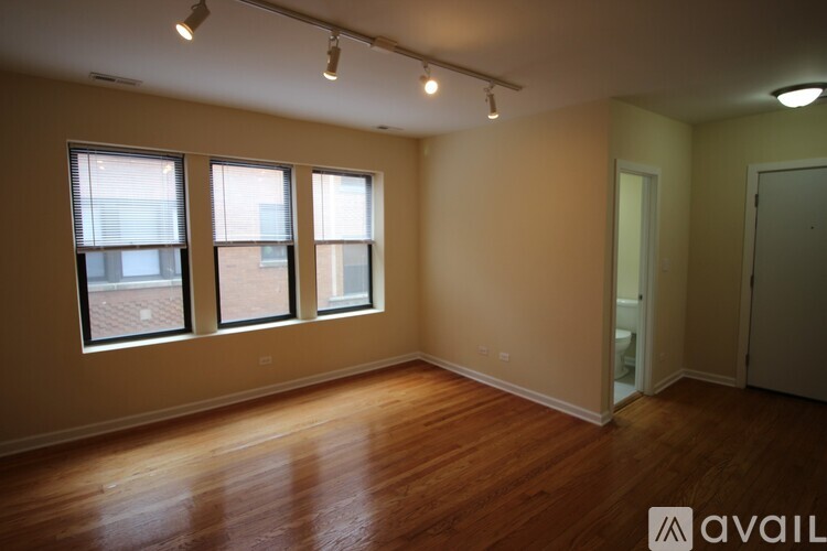 A room with wooden floors and three windows.