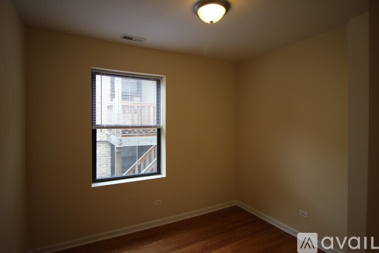 A room with a window and wooden floors is available for rent.