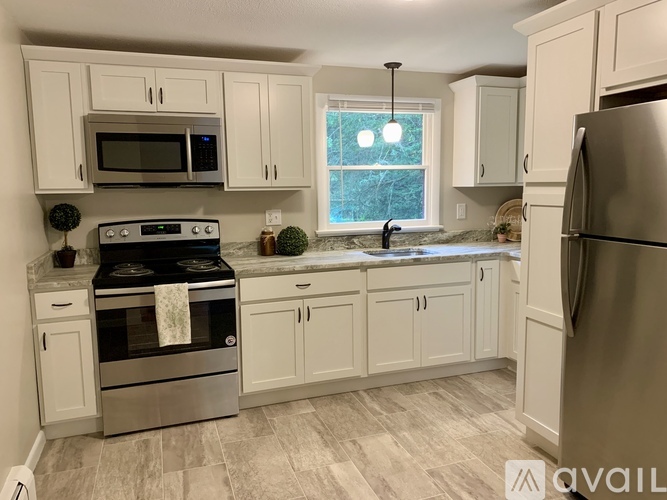 A kitchen with white cabinets and a stainless steel refrigerator.