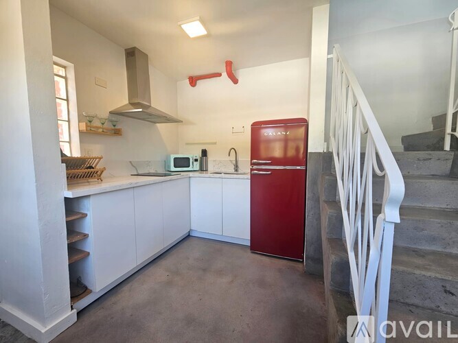 A kitchen with white cabinets and a red fridge.