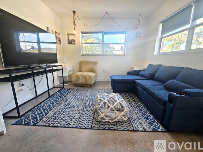 A living room with a dark blue couch, a television, and a rug.