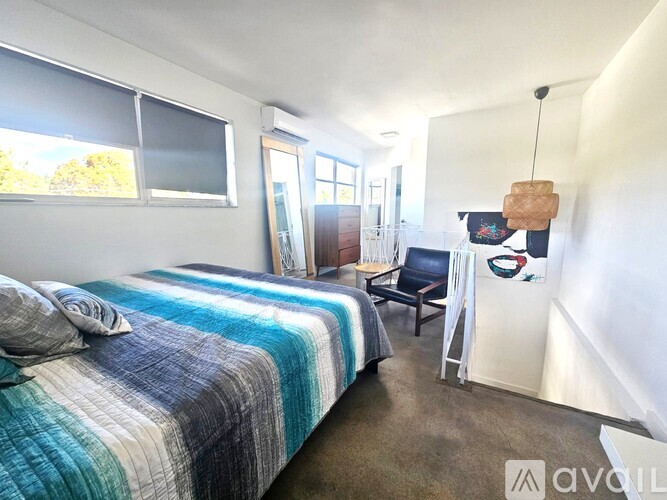 A bedroom with a bed, chair, and a hanging light fixture.