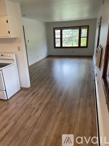 A kitchen with a white dishwasher and wooden flooring.