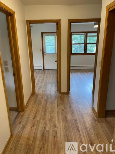 A hallway with wooden floors and white walls.