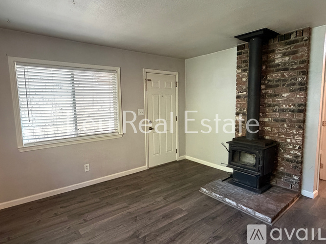 A room with a wood stove and a window with blinds.