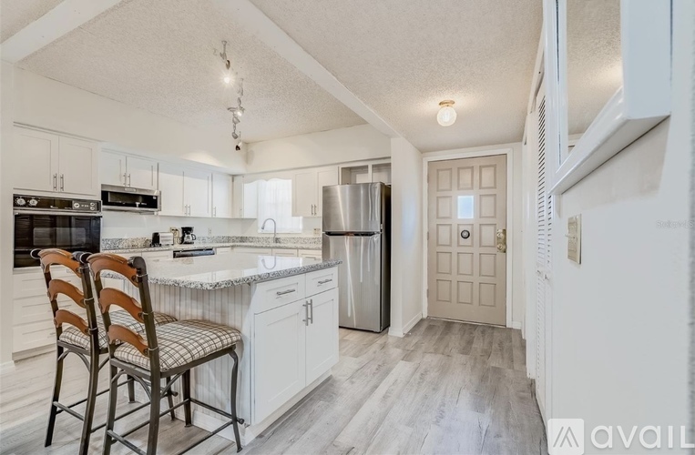 A kitchen with a refrigerator, sink, and cabinets.