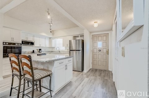 A kitchen with a refrigerator, sink, and cabinets.
