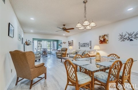 A dining room with a table set for six and a ceiling fan.