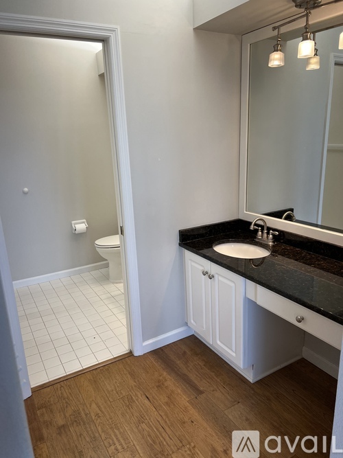 A bathroom with a toilet, sink, and mirror.