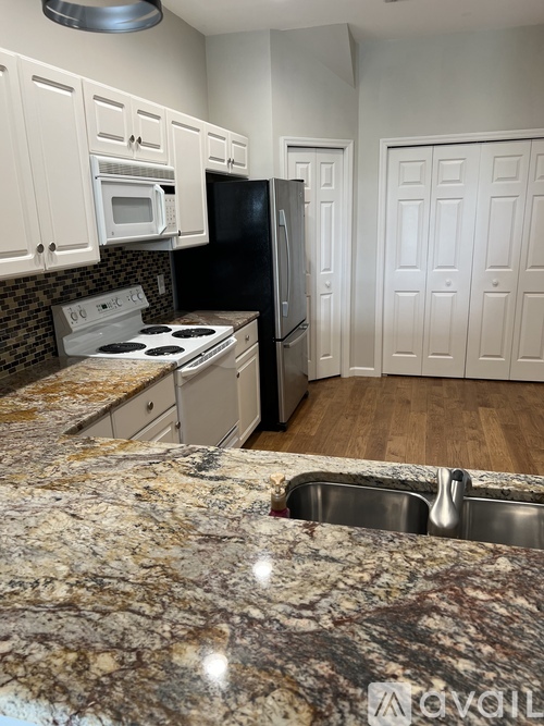 A kitchen with granite countertops and white cabinets.