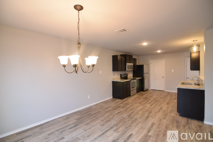 A well-lit room with a chandelier and a kitchenette.