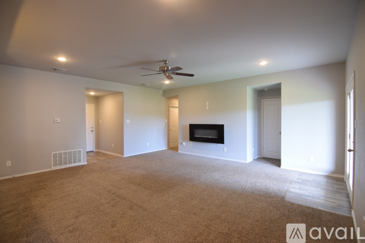 A spacious living room with a television and a ceiling fan.