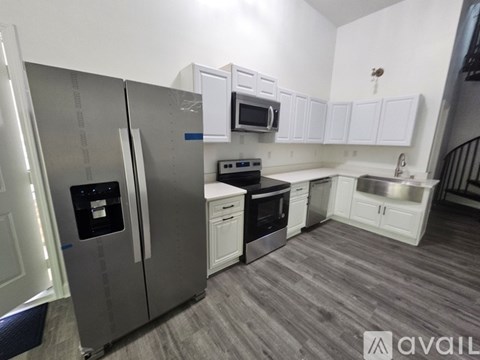 A kitchen with a stainless steel refrigerator and white cabinets.