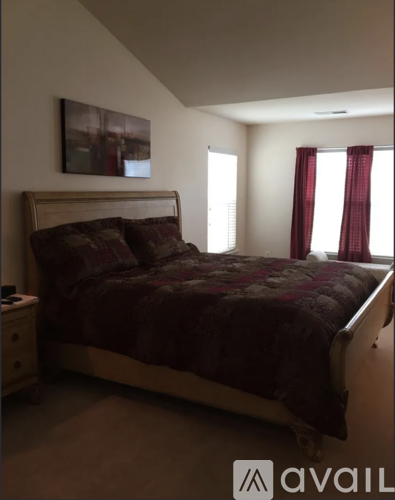 A bedroom with a large bed and a window with red curtains.