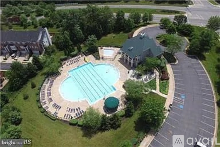 An aerial view of a swimming pool surrounded by a grassy area and a building in the background.