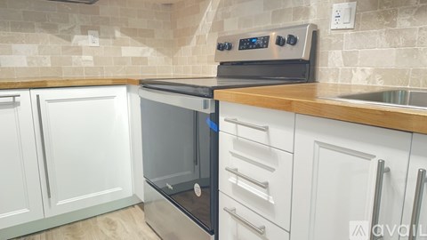 A modern kitchen with a stainless steel oven and white cabinets.