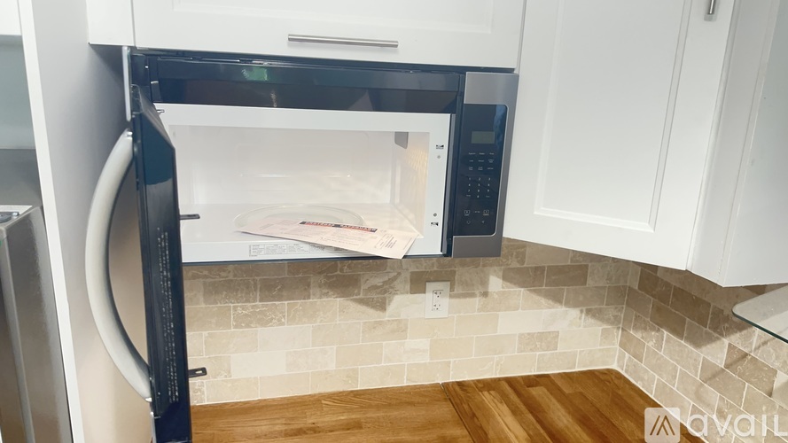 A modern kitchen with a black fridge and white cabinets.