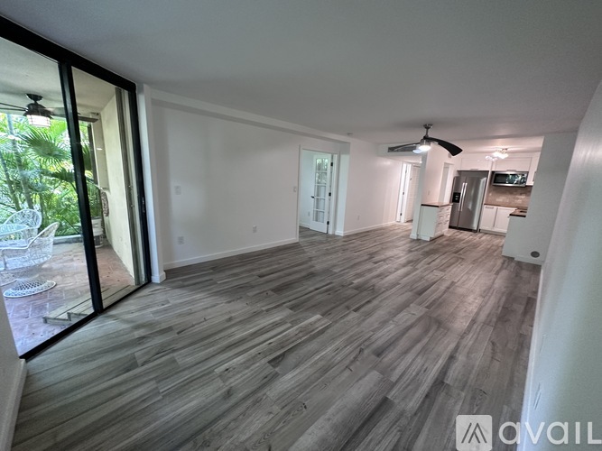 A spacious room with wooden flooring and sliding glass doors leading to a balcony.