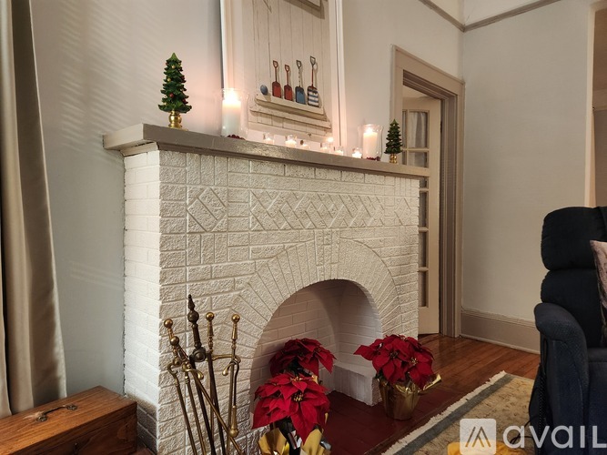 A fireplace with a Christmas tree and candles on top.