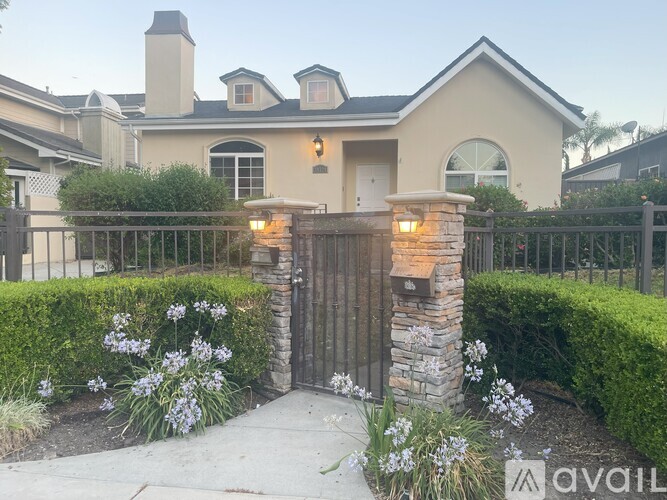 A house with a stone pillar and gate in front of it.
