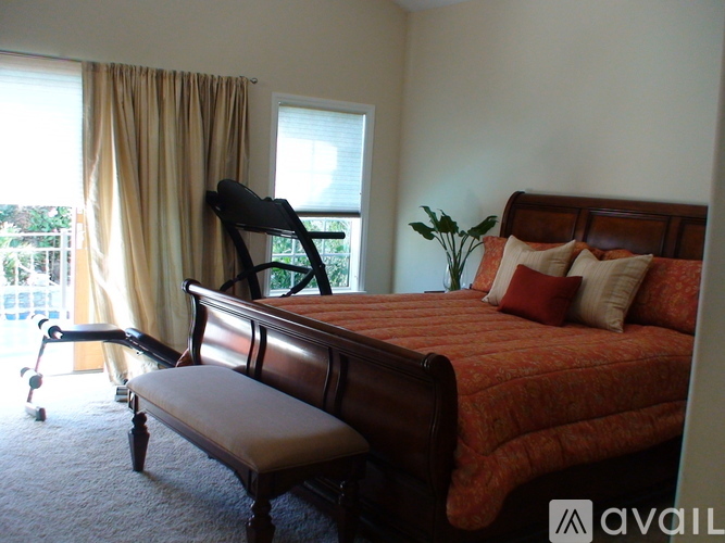 A bedroom with a bed, chair, and window.