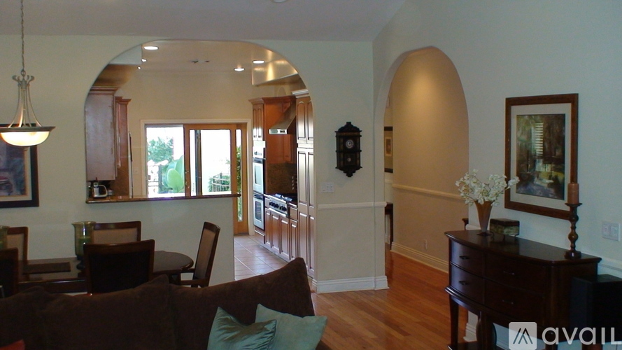A living room with a brown couch and a chandelier.