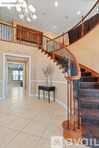 A spacious foyer with a curved staircase and a chandelier.