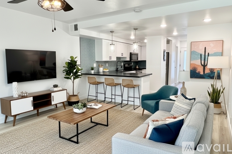 A living room with a grey couch, a wooden coffee table, and a flat screen TV mounted on the wall.