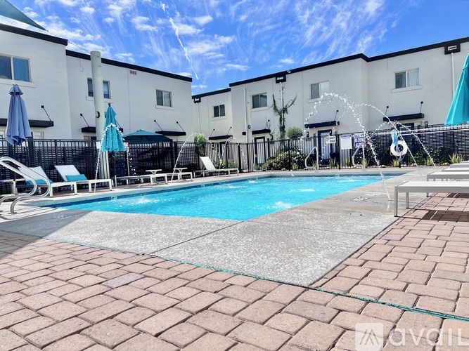 A swimming pool surrounded by a black fence and a brick patio.
