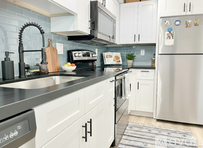 A modern kitchen with white cabinets and a stainless steel refrigerator.