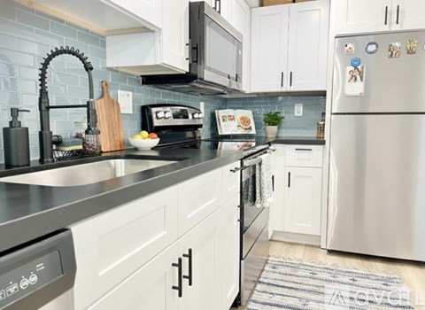 A modern kitchen with white cabinets and a stainless steel refrigerator.