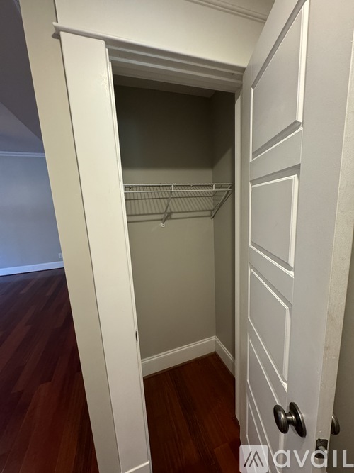 A white closet with a door and a shelf.
