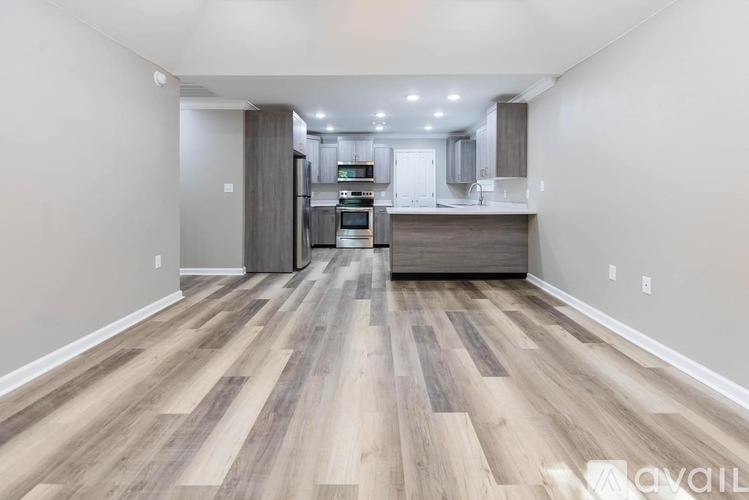 A kitchen with a wooden floor and a refrigerator.